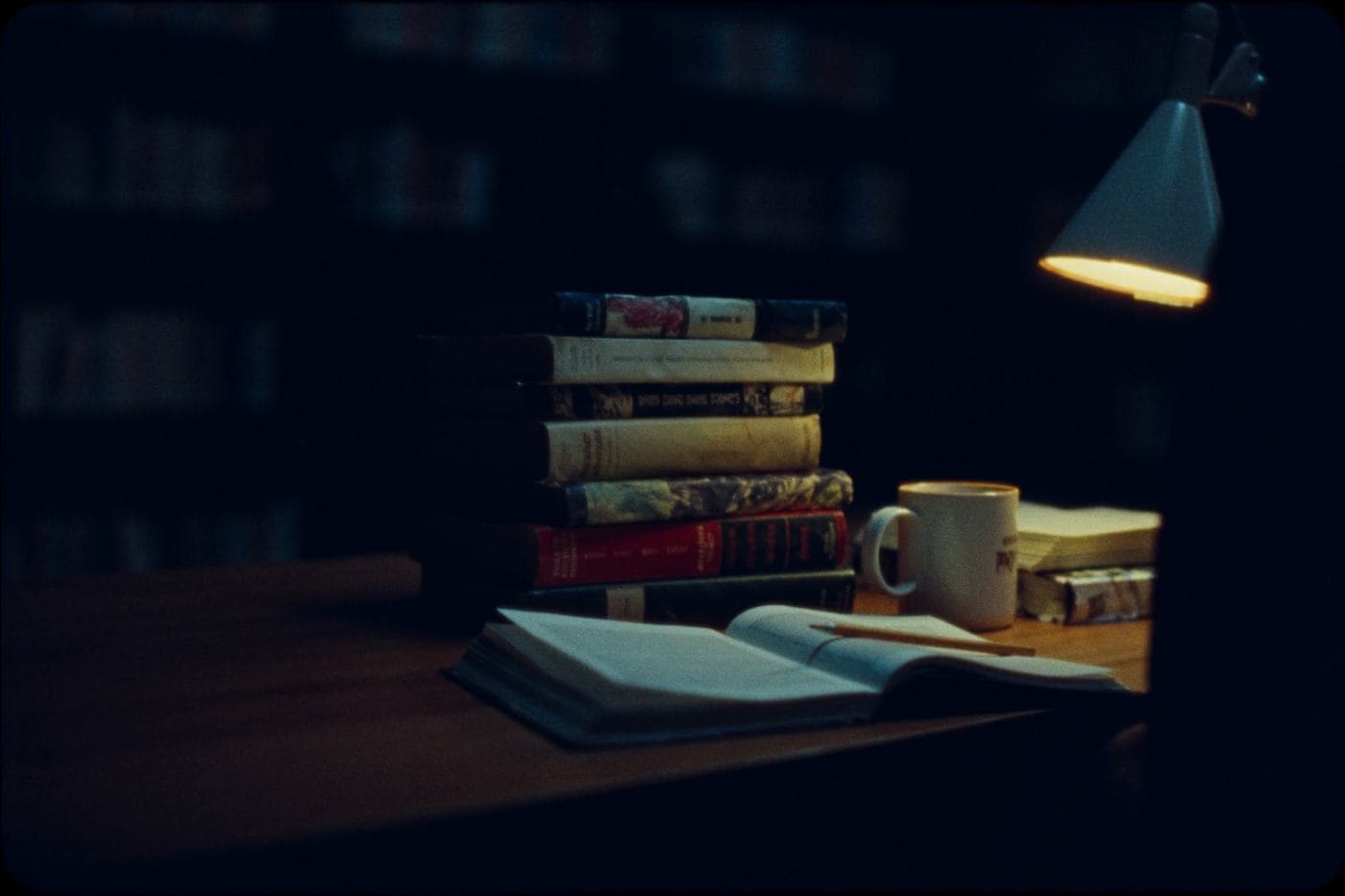 Books and an open reading on a library table at night
