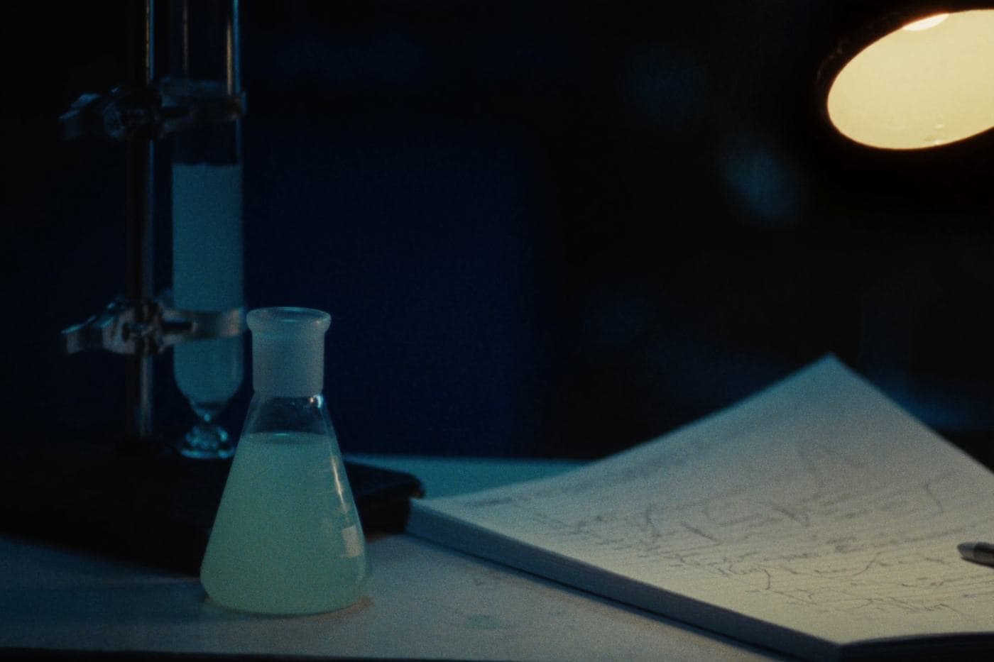 A burette and flask on a chemistry bench under a lamp